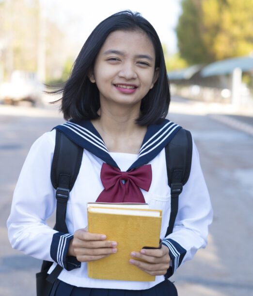 Beautiful Asian student hold book at school.