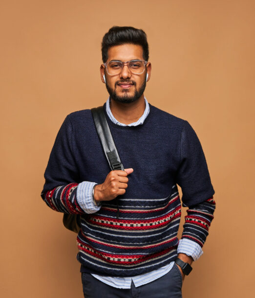 Young bearded hindu student with backpack on pastel background.